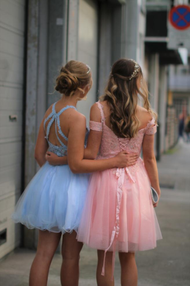 Nydelig kort, ballkjole i fargen Ice Blue. Utsmykket halter-topp med blå stener og blomster. Kort tulle skjørt med flere lag under.