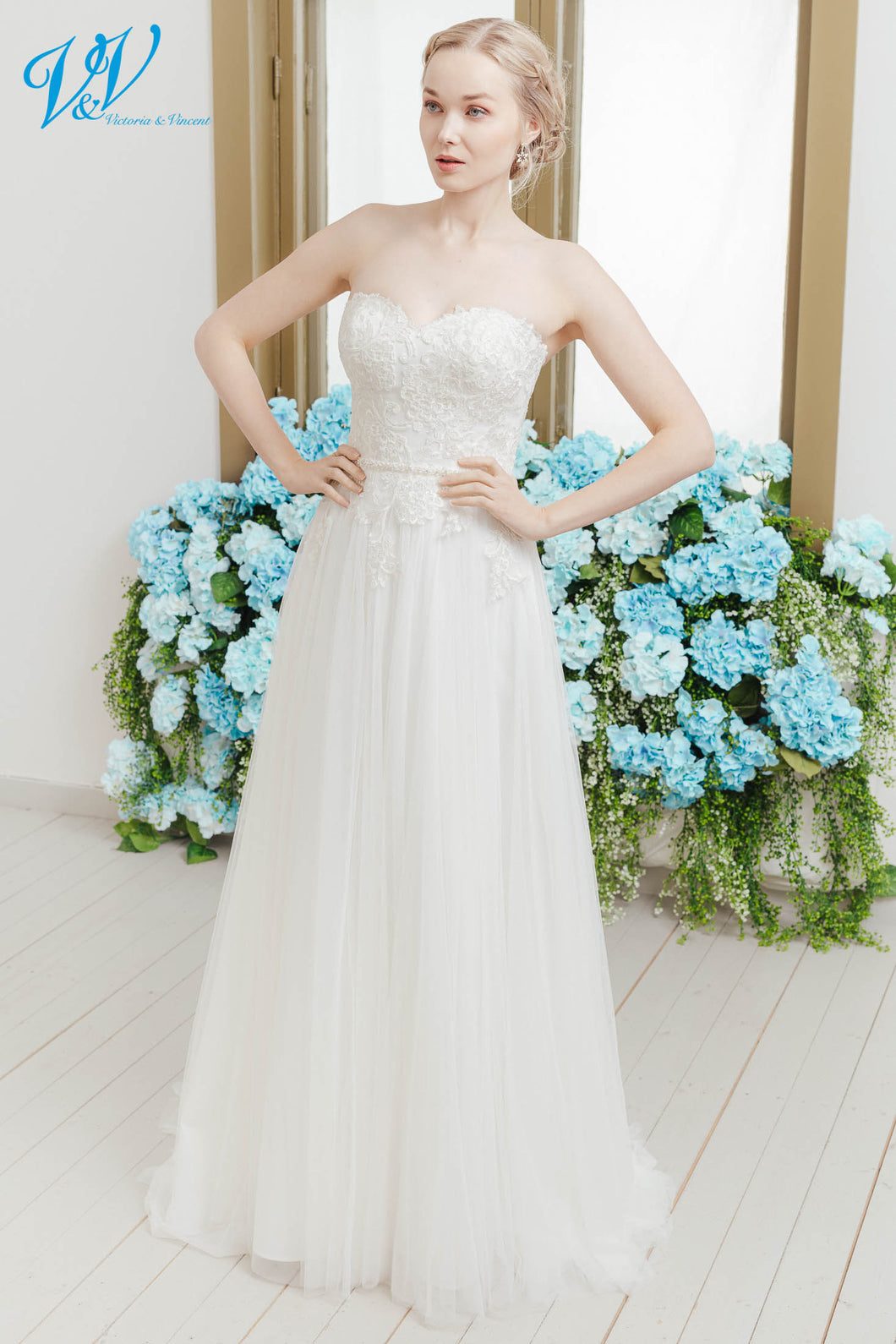 En nydelig og romantisk brudekjole med hjertetopp og blonder. Et glitrende belte markerer midjen.
