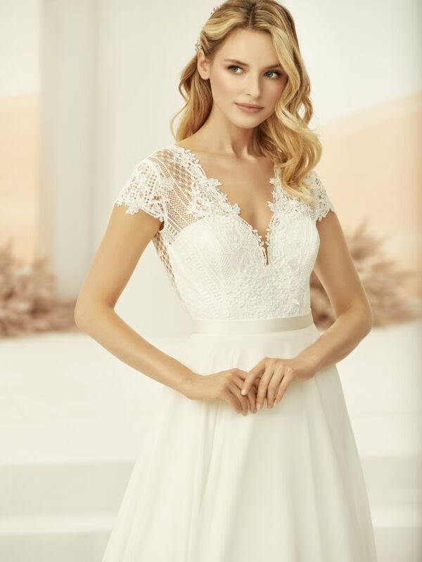 Brudekjolen Drina er en elegant kjole med v-hals med en åpen blonde rygg. 